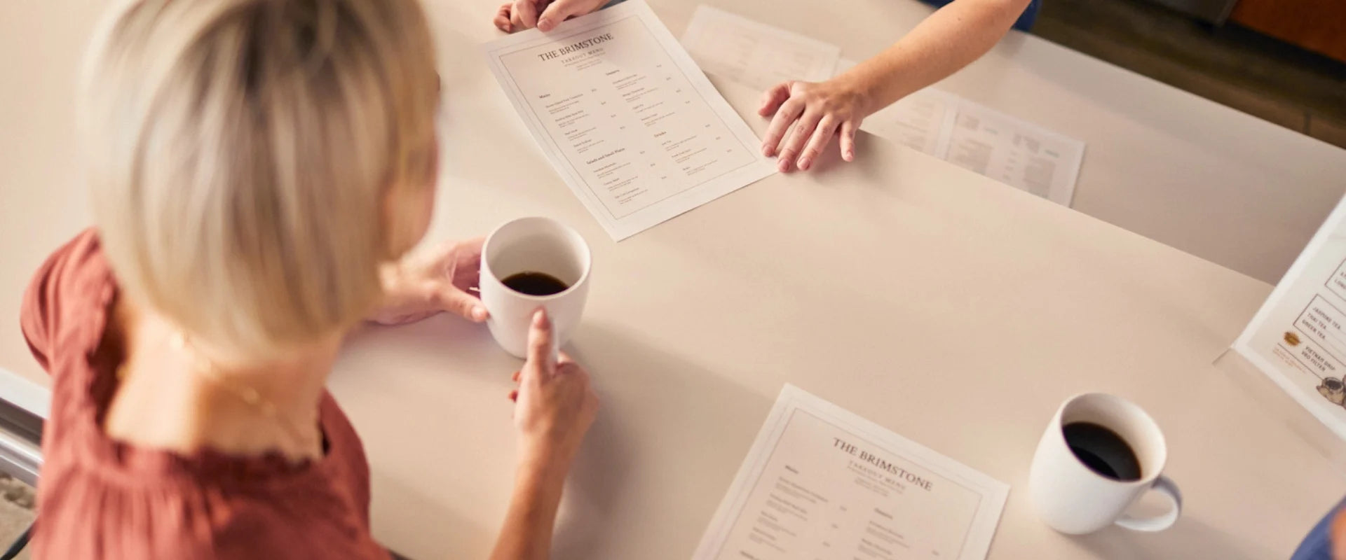 Woman with a cup of coffee looking at a menu