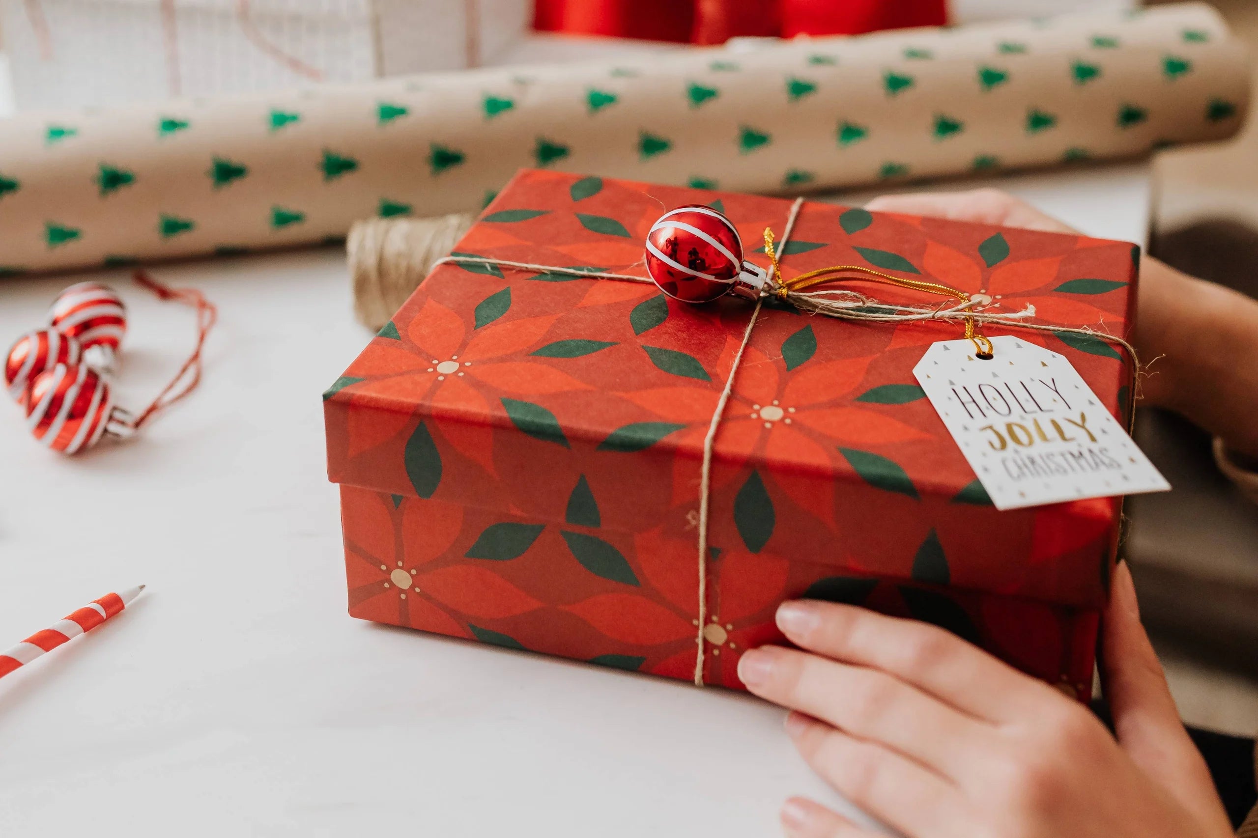 Closeup of a wrapped Christmas present with a gift tag that says Holly Jolly Christmas