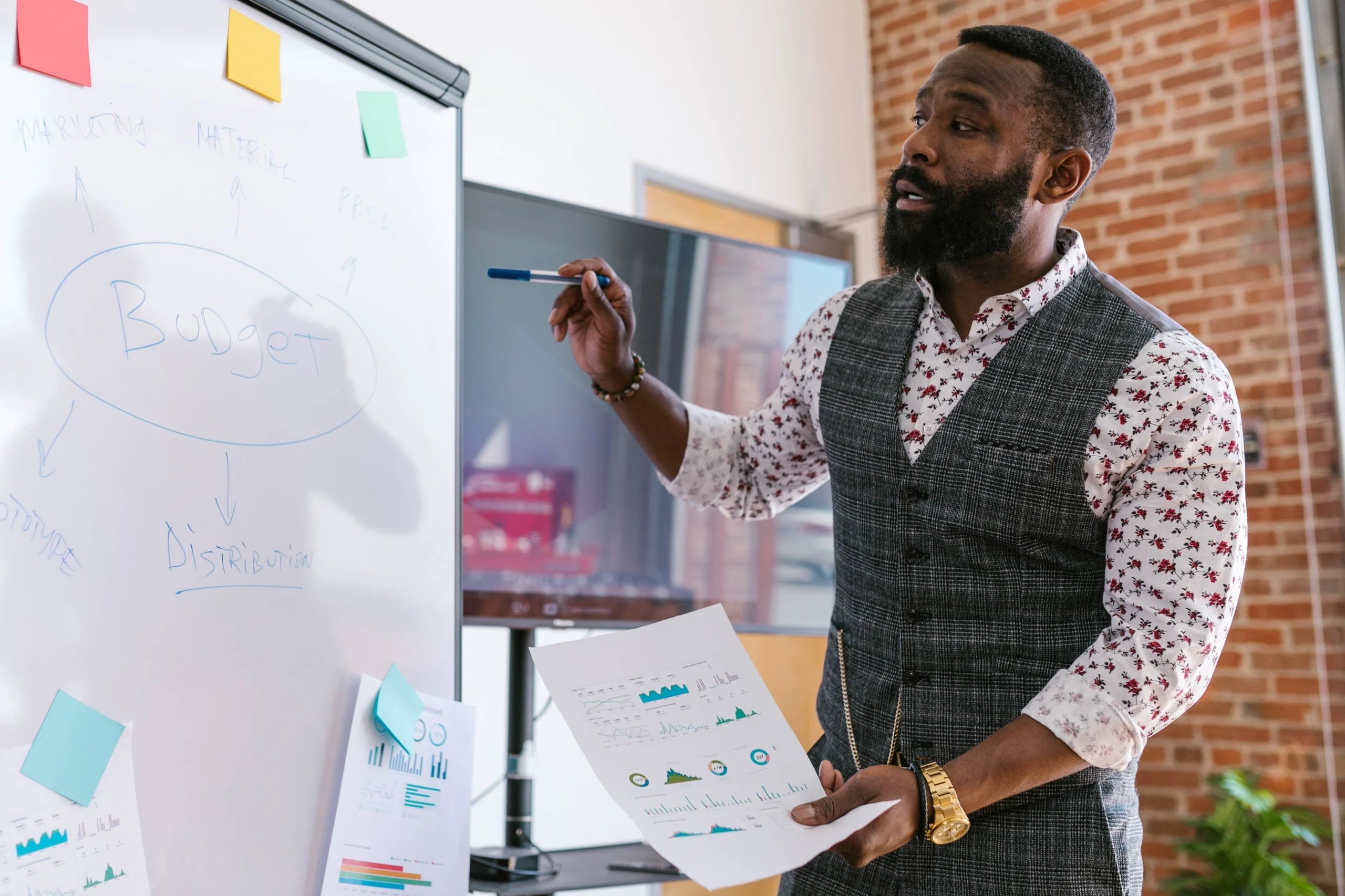 Man holding paper and writing on a whiteboard.