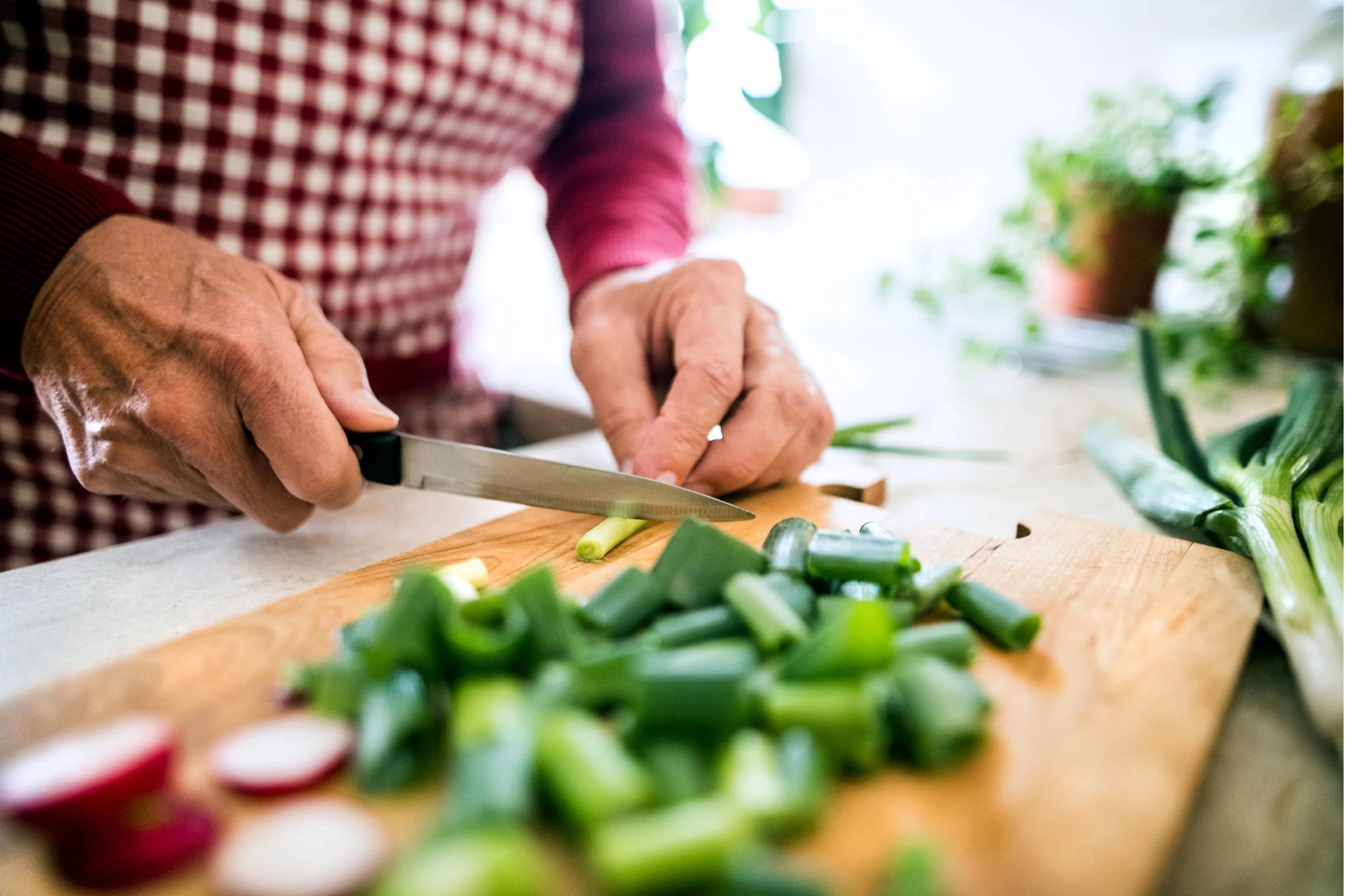 Closeup of someone chopping green onions on a cutting board