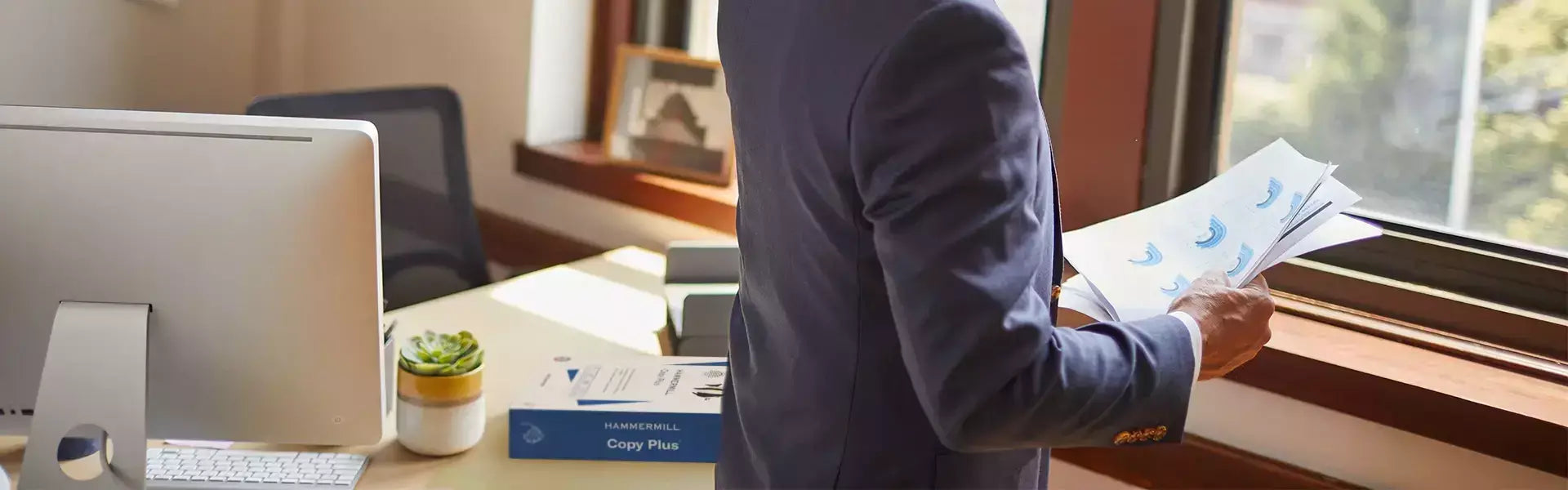 Person standing in an office looking at reports