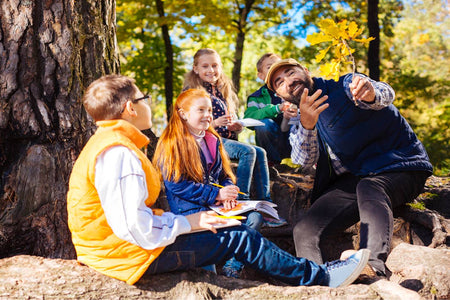 Teacher explaining something to students next to a tree