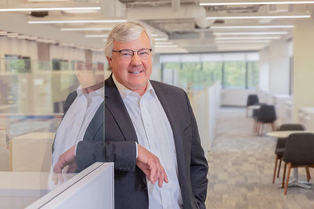 Man in a suit in an office posing for a photo.