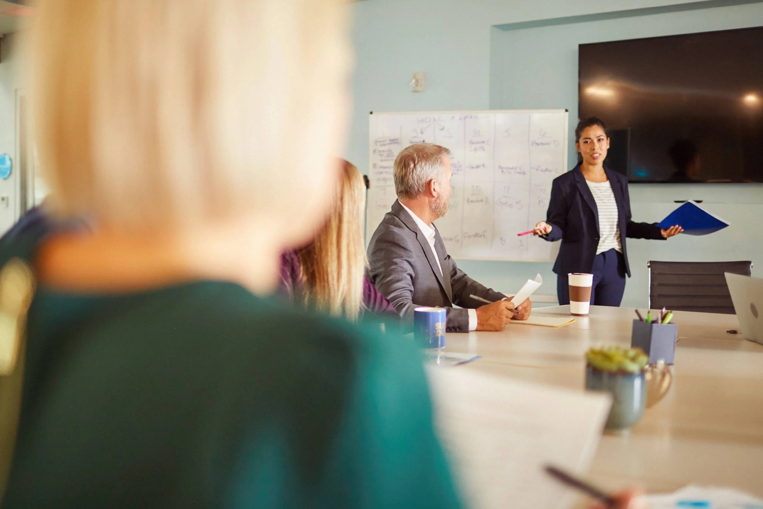 Coworkers in a meeting with one standing up and presenting.