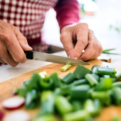 Closeup of someone chopping green onions on a cutting board