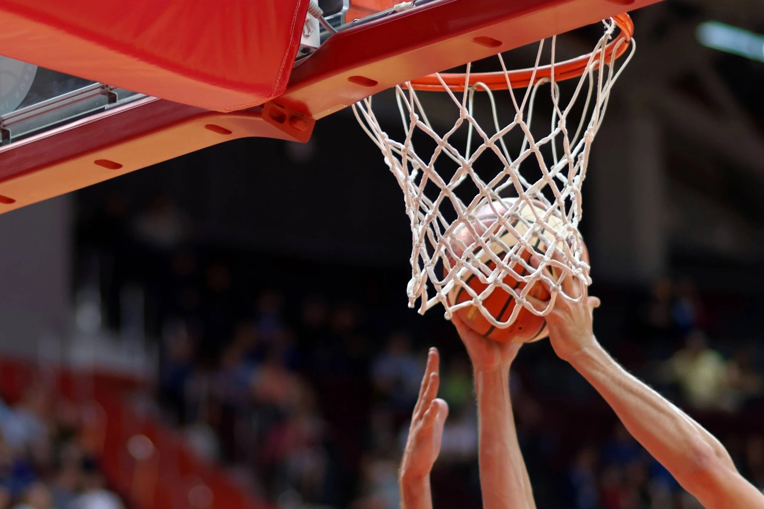 Basketball player getting rebound from basketball hoop.